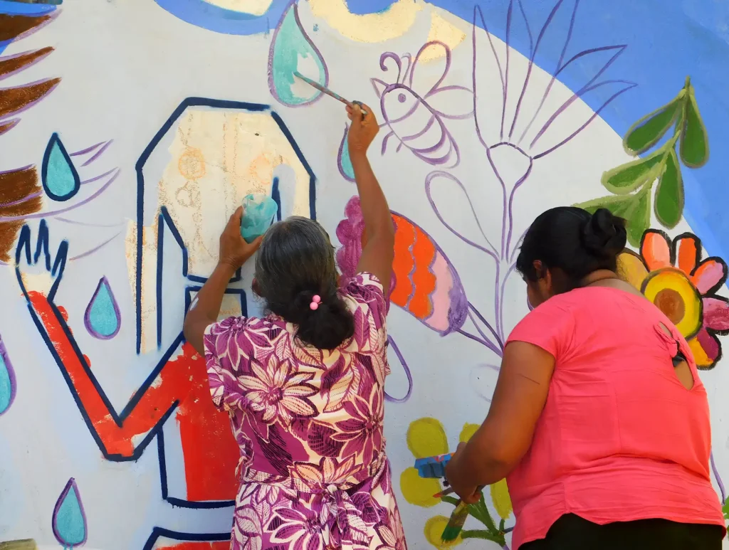 Running for water. Rosalina and another woman from the community painting a mural in Teocuatlán, San José Tenango, in Oaxaca, Mexico.